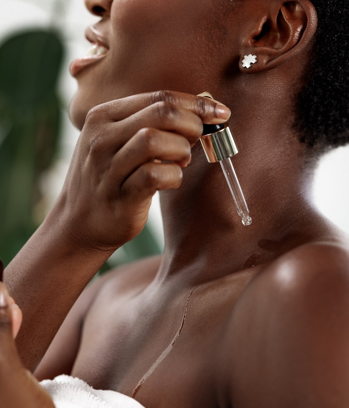 A woman applying Navéh Olive botanical oil with a glass dropper